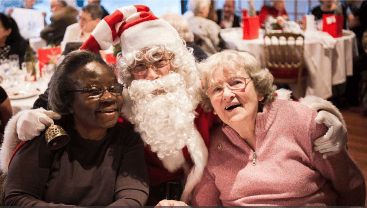 Des bénéficiaires des repas solidaires de l'association Petits Frères de Pauvres font une photo avec le Père Noël