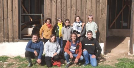 7 femmes et 3 hommes posent et sourient devant un ancien séchoir à tabac en bois