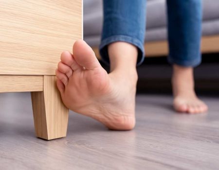 Pieds qui se cognent dans un meuble - source : Dall-E