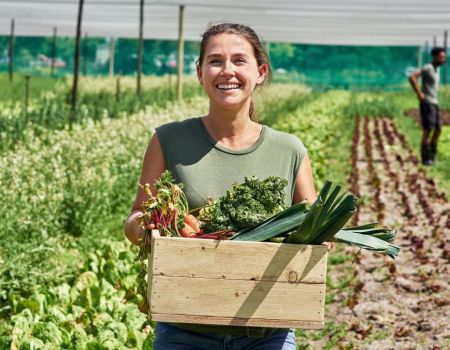Une femme qui vient de récolter des légumes.