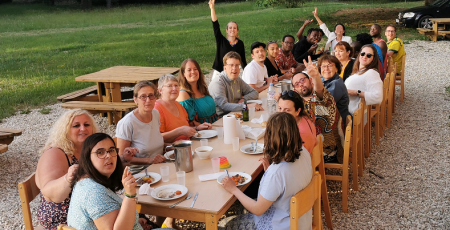 photo d'un repas en extérieur, devant une bâtisse l'ambiance est joyeuse