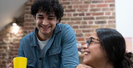 Deux jeunes sourient ensemble, dans un bureau.