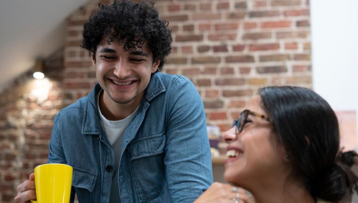 Deux jeunes sourient ensemble, dans un bureau.