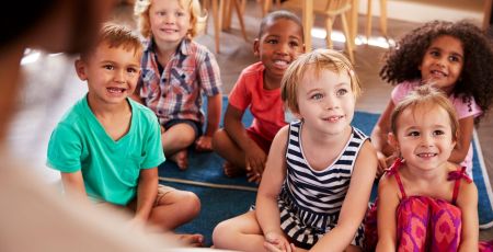 Teacher At Montessori School Reading To Children At Story Time