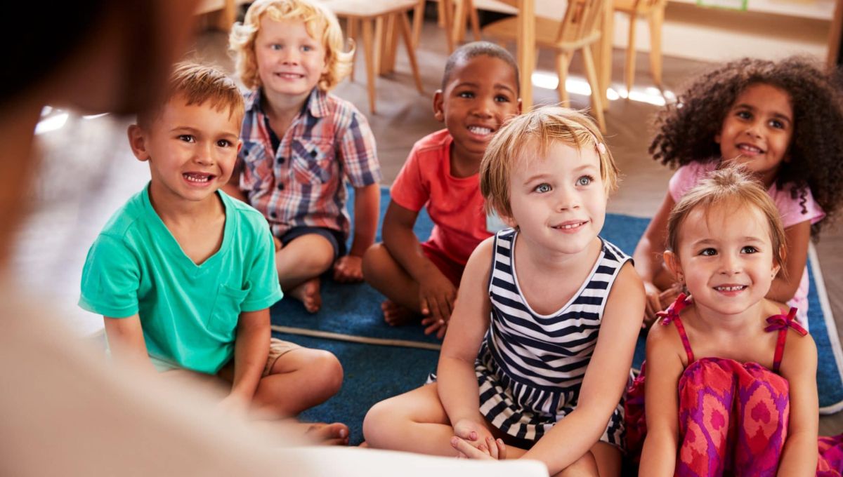 Teacher At Montessori School Reading To Children At Story Time