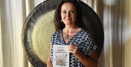 Sylvie Captain-Sass est devant un gong. Elle a entre ses mains son livre Le cerveau ou la fabrique du bonheur
