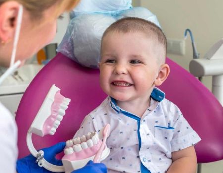 Un petit garçon sourit de toutes ses dents chez le dentiste.