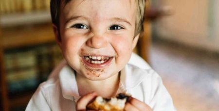 Petit garçon souriant mangeant un pain au chocolat.
