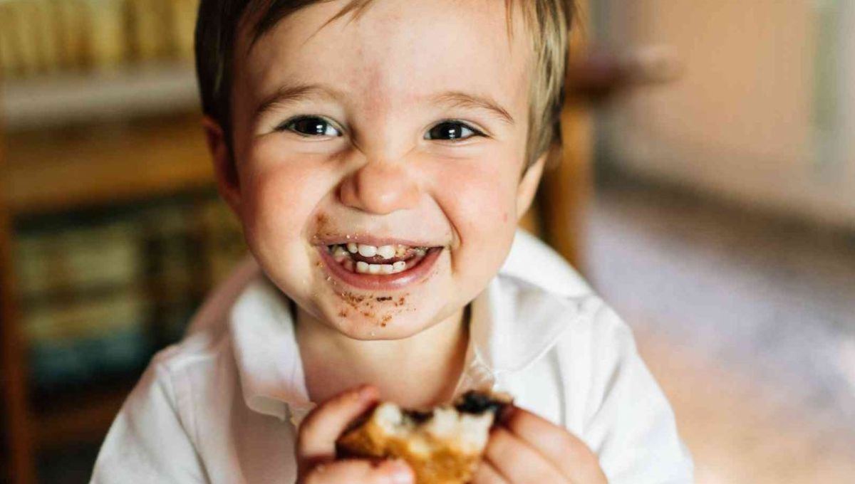 Petit garçon souriant mangeant un pain au chocolat.