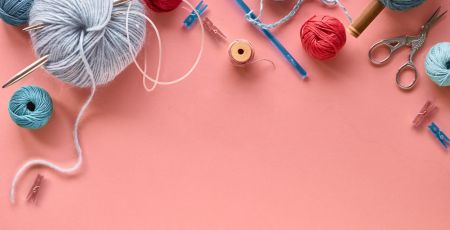 Various wool yarn and knitting needles, creative knitting hobby background with text space