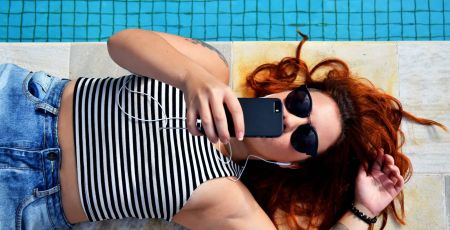 Une femme écoute de la musique au bord d'une piscine.