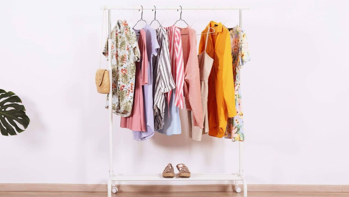 Women's hip clothing store interior concept. Row of different colorful female clothes hanging on rack in hipster fashion show room in shopping mall. White wall background. Copy space.